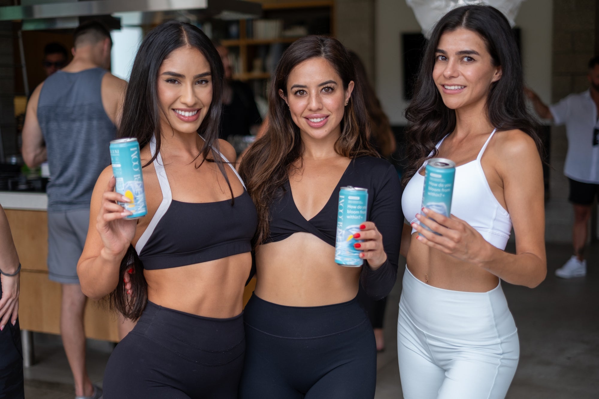 Three women in athletic wear holding Innerbloom cans in an indoor setting
